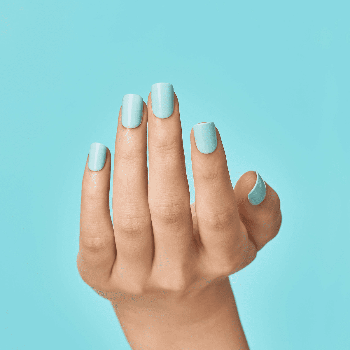 A hand modeling short, square false nails in a shiny, light turquoise color by imPRESS