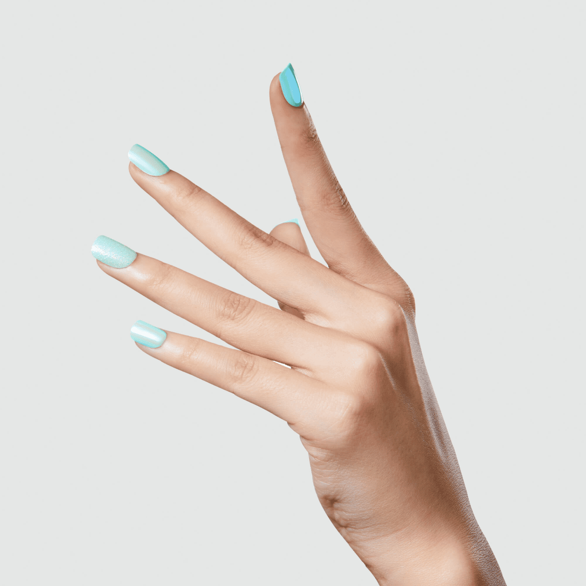 Hand displaying turquoise shimmer nail polish on almond-shaped nails against white background.