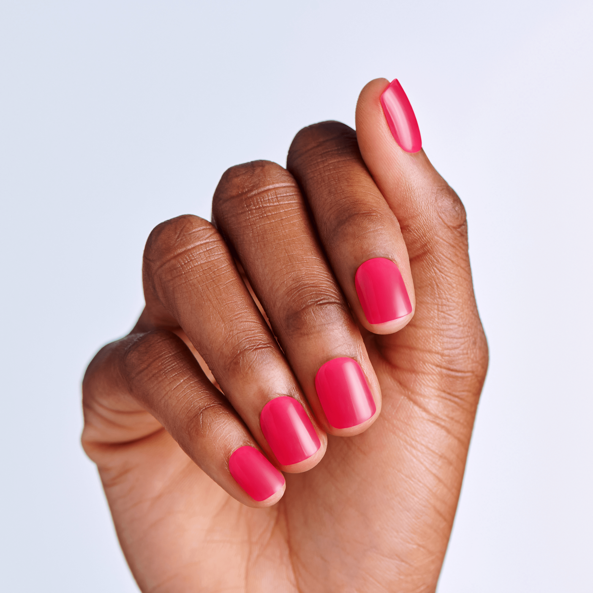 Hand with pink press on manicure on a light purple background