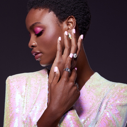 A woman modeling shimmery, pink nails in short, squoval shape. Press-on nails are style, &