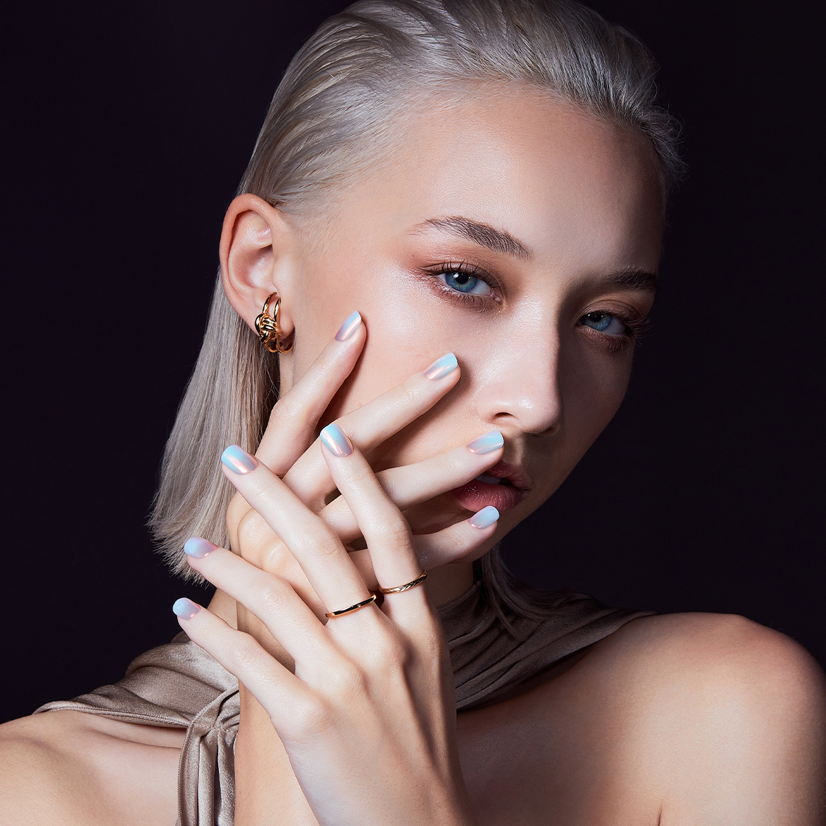 A woman with her hands by her face, modeling press-on nails in &