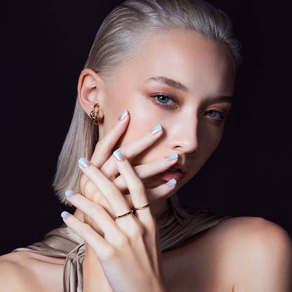 A woman with her hands by her face, modeling press-on nails in &