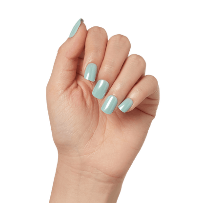 A hand modeling short, squoval press on nails in mint green with mirror, powdered effect. Nails are &