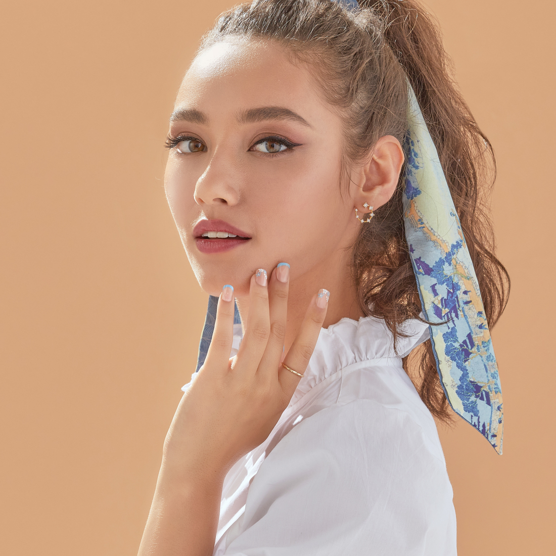 A model displaying medium squoval shaped nails in varying blue and white with floral designs