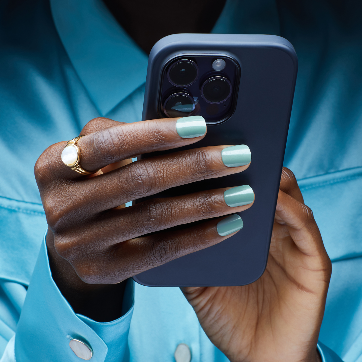 Person modeling short, squoval press on nails in mint green color and a mirrored, powder effect. Nails are &