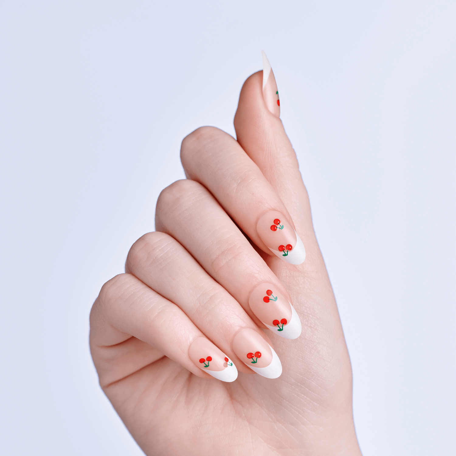 Hand with nails featuring cherry nail art on a light purple background