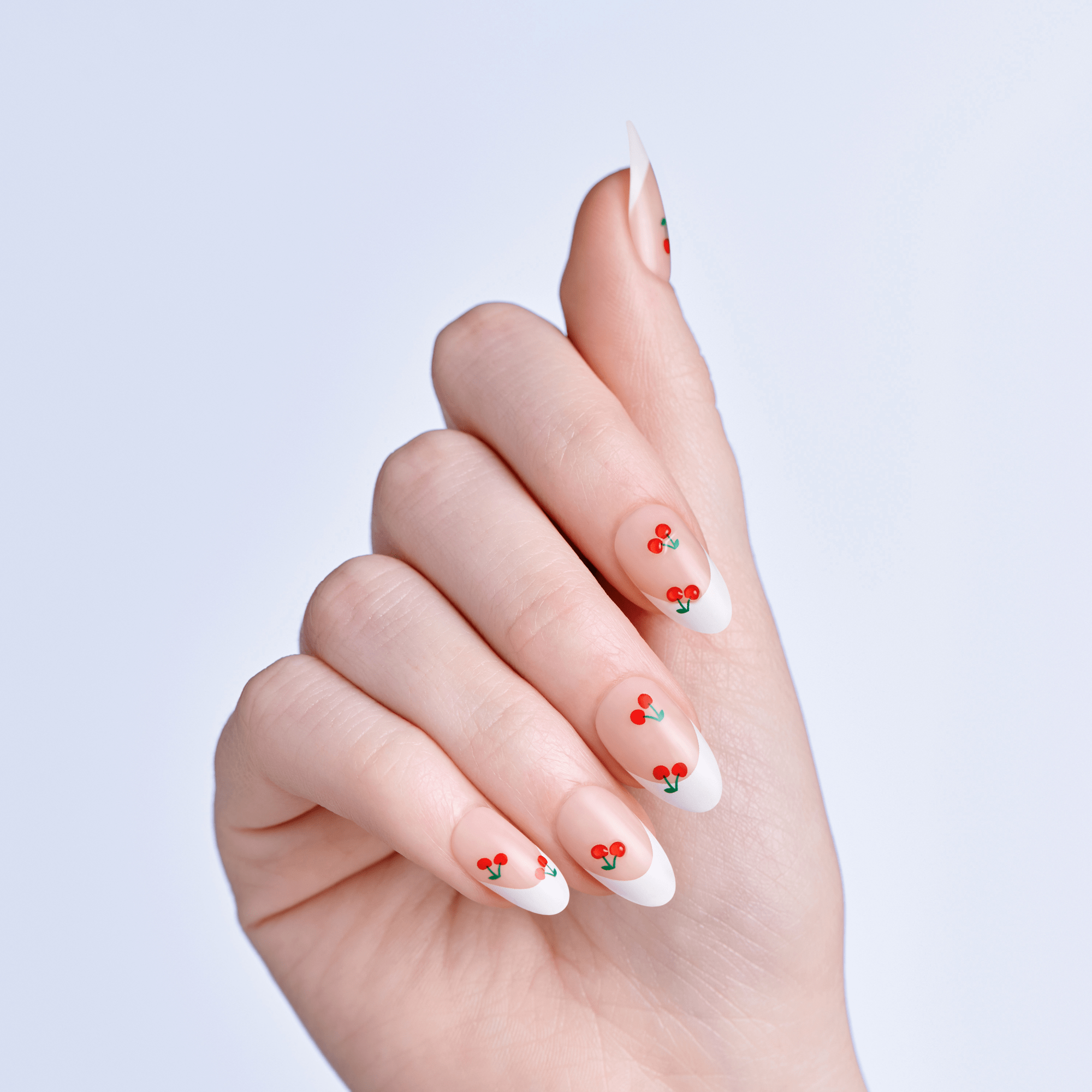 Hand with nails featuring cherry nail art on a light purple background