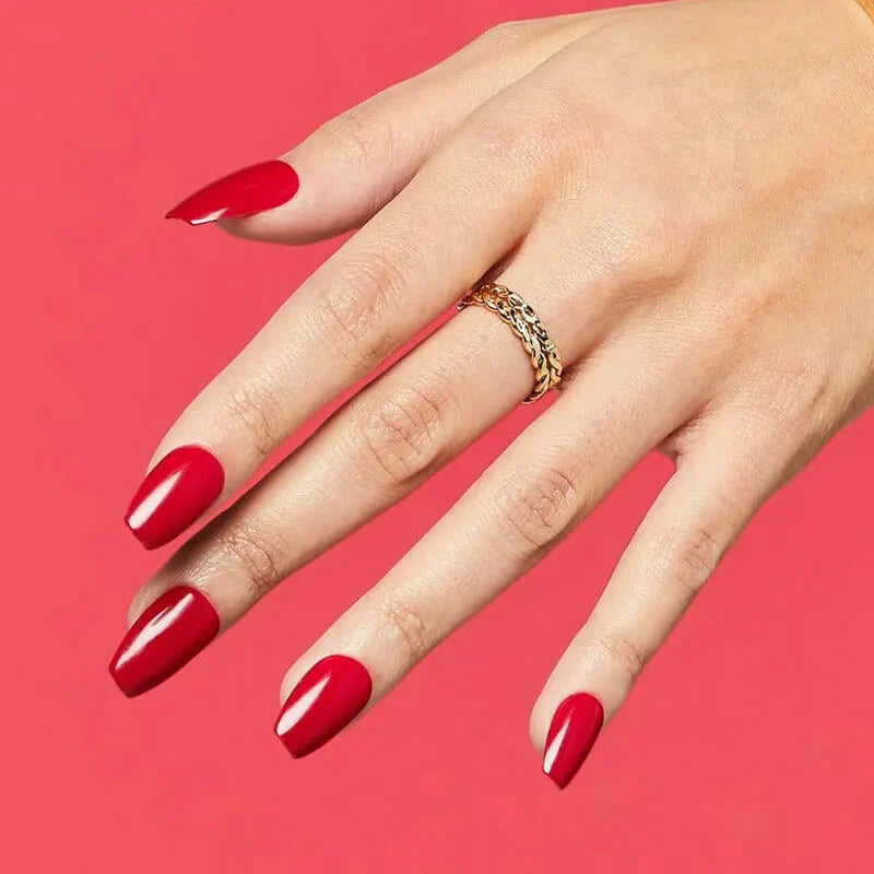 A hand modeling a press on manicure from imPRESS. Nails are medium, squoval shape in a shiny, blue tone red color. Nails look professional and last up to 7 days.