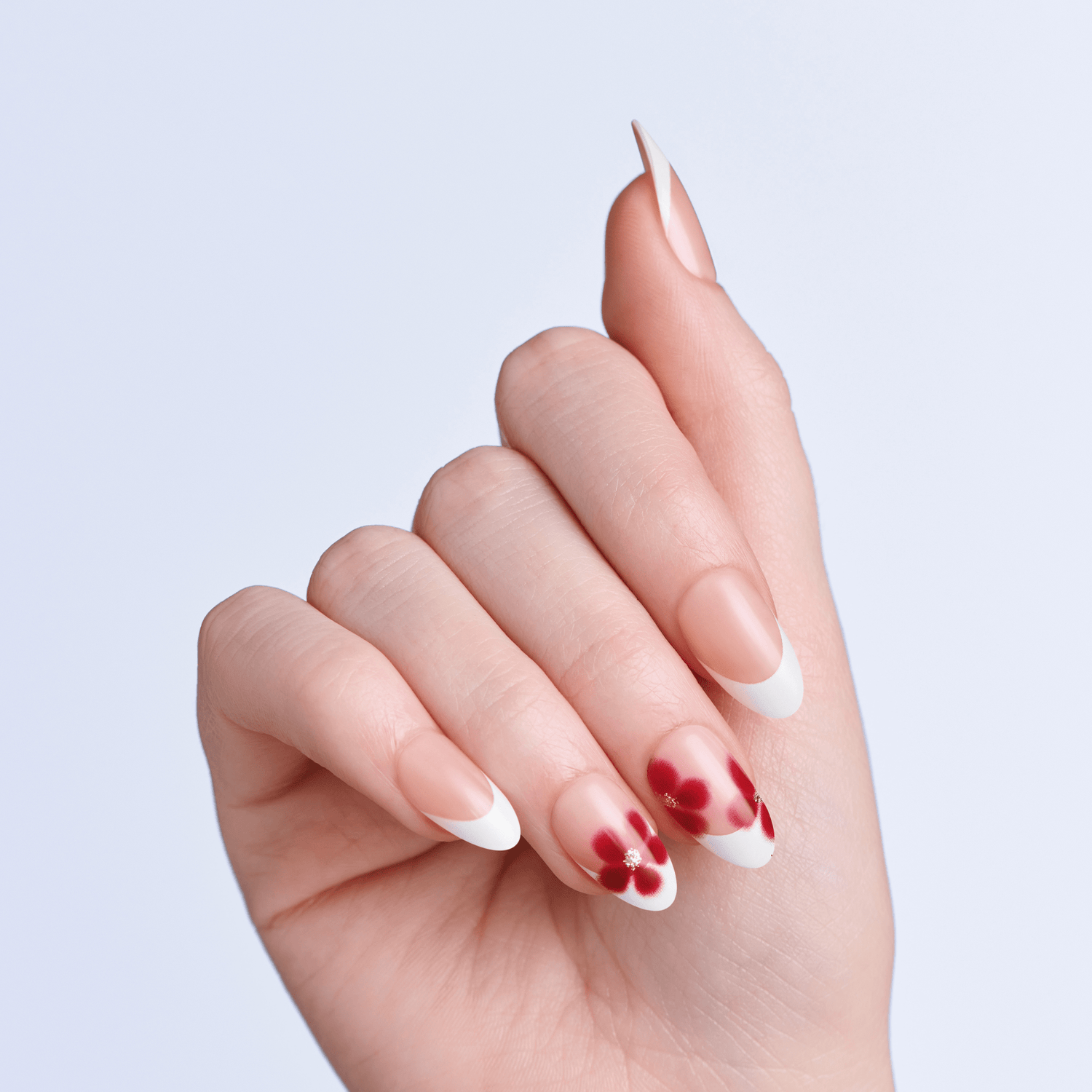 Hand with red and white press on nails on a light gray background