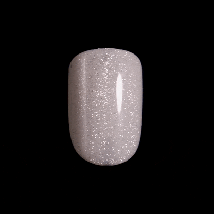Close-up, moving image of a single, sparkly, white, press-on nail in short, squoval shape. Nail is from imPRESS ColorFX in &