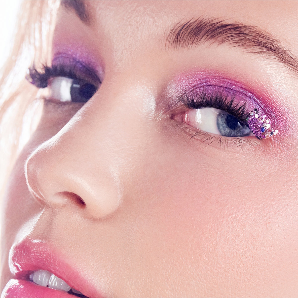 Close-up of eye makeup with pink and purple eyeshadow and glitter detail.