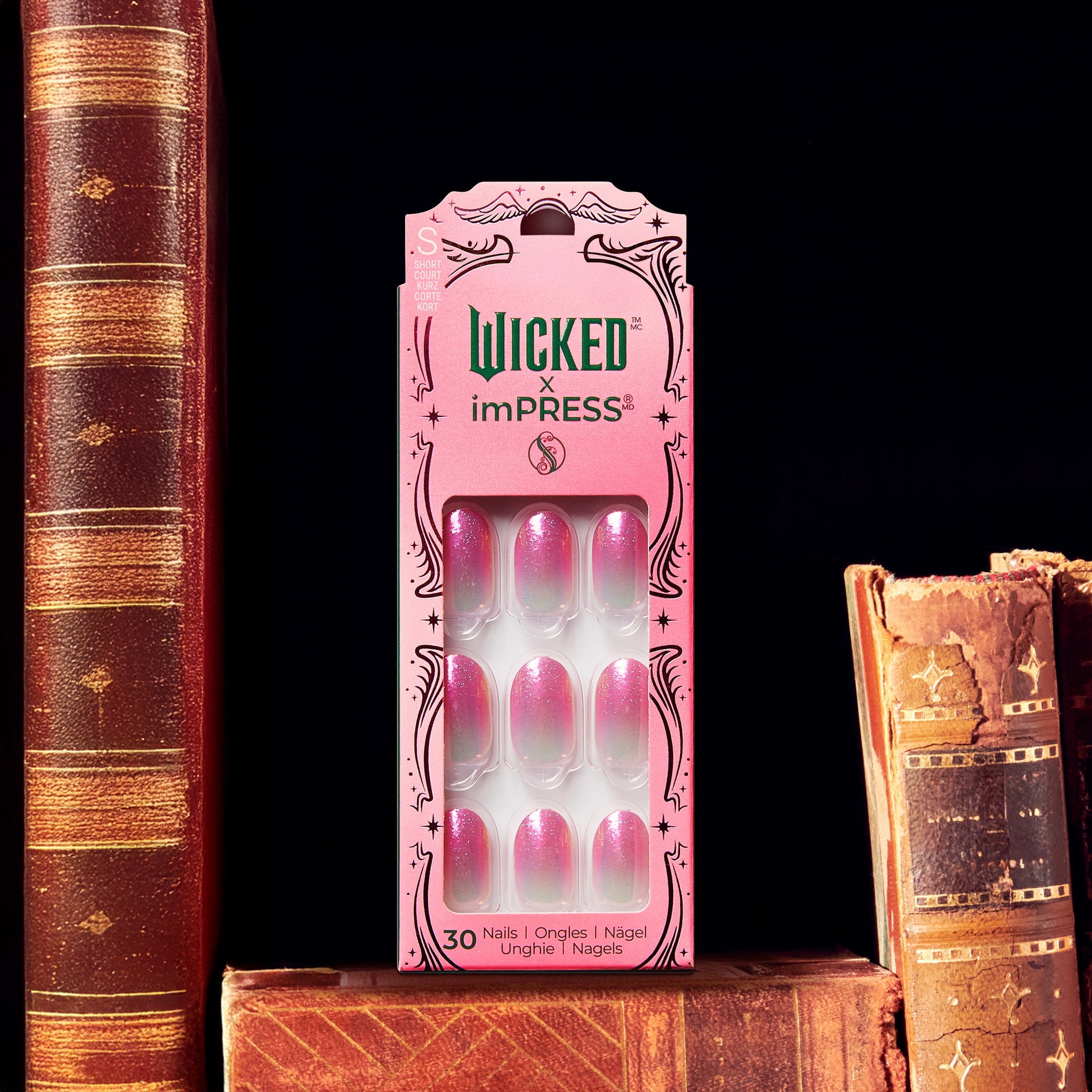 Wicked x imPRESS press-on nails in pink ombre, 30 count, displayed with vintage books.
