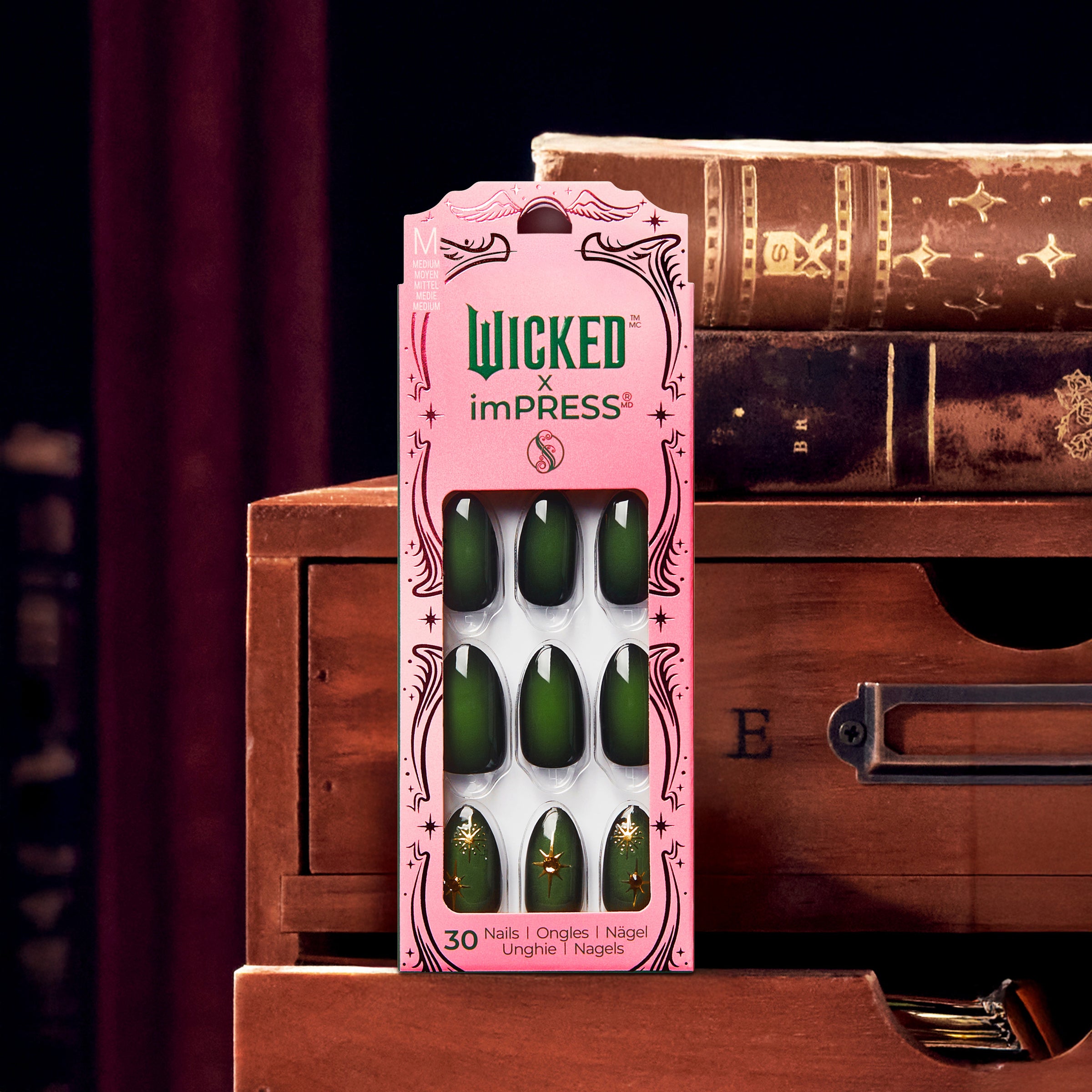 Wicked x imPRESS nail set with 30 green nails, displayed on vintage books.