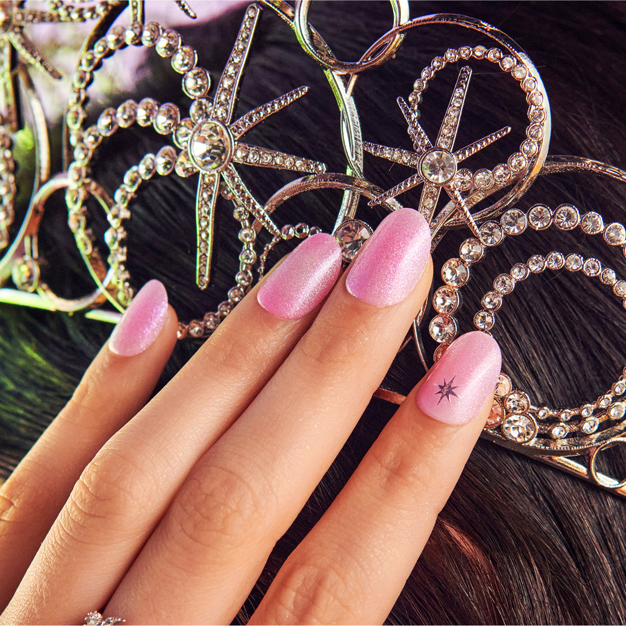 Pink glitter nails with star accent nail and rhinestone jewelry backdrop.