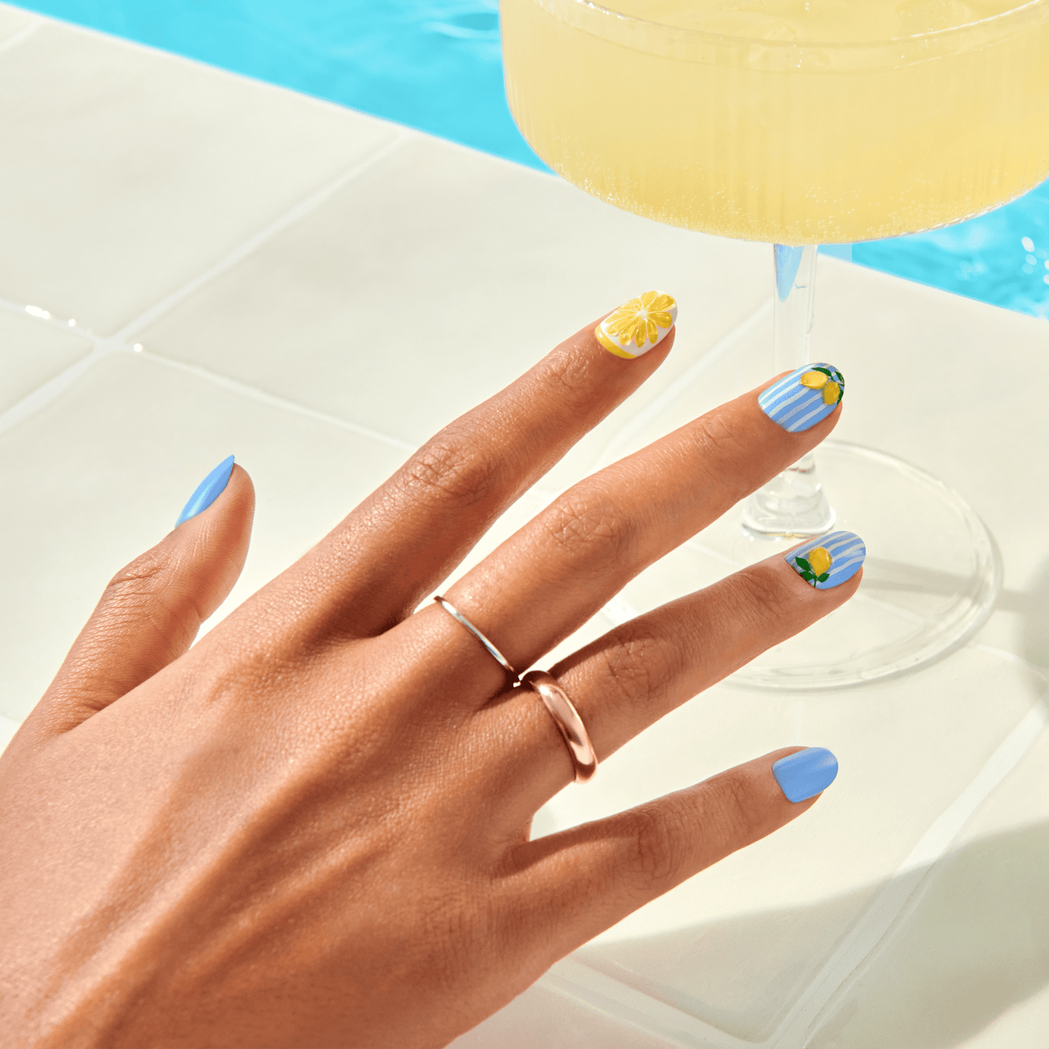 Hand with colorful nail art holding a cocktail 
