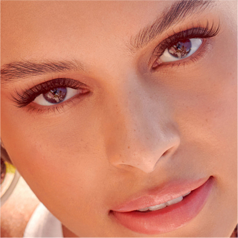 Close-up of woman's face wearing imPRESS Demi Natural false lashes and pink lipstick.