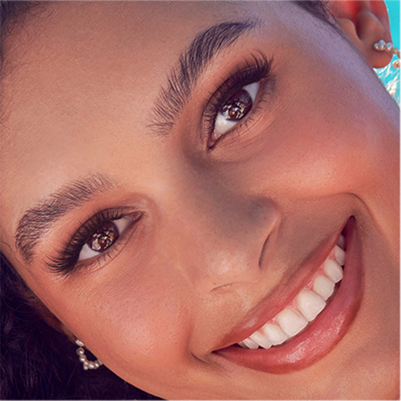 Close-up of woman wearing imPRESS Demi Wispy false lashes and smiling.