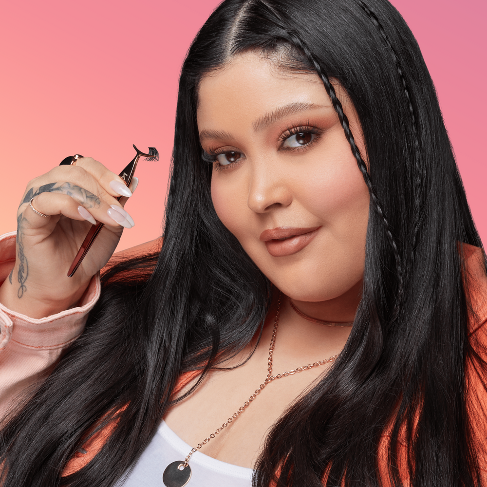 A woman with beautiful eye makeup and imPRESS falsies holding up a lash applicator tool with a lash cluster in it. The image indicates that she'll be showing off how to apply imPRESS lashes. 
