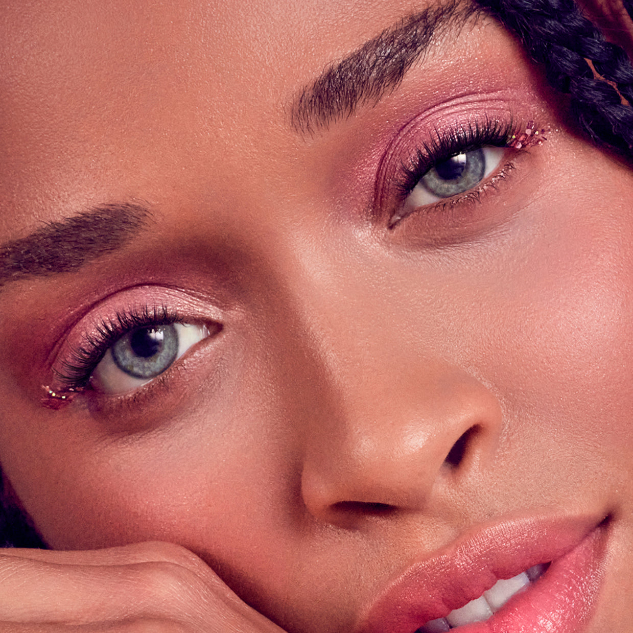 Close-up of woman's face showcasing full lashes and pink eyeshadow makeup look.