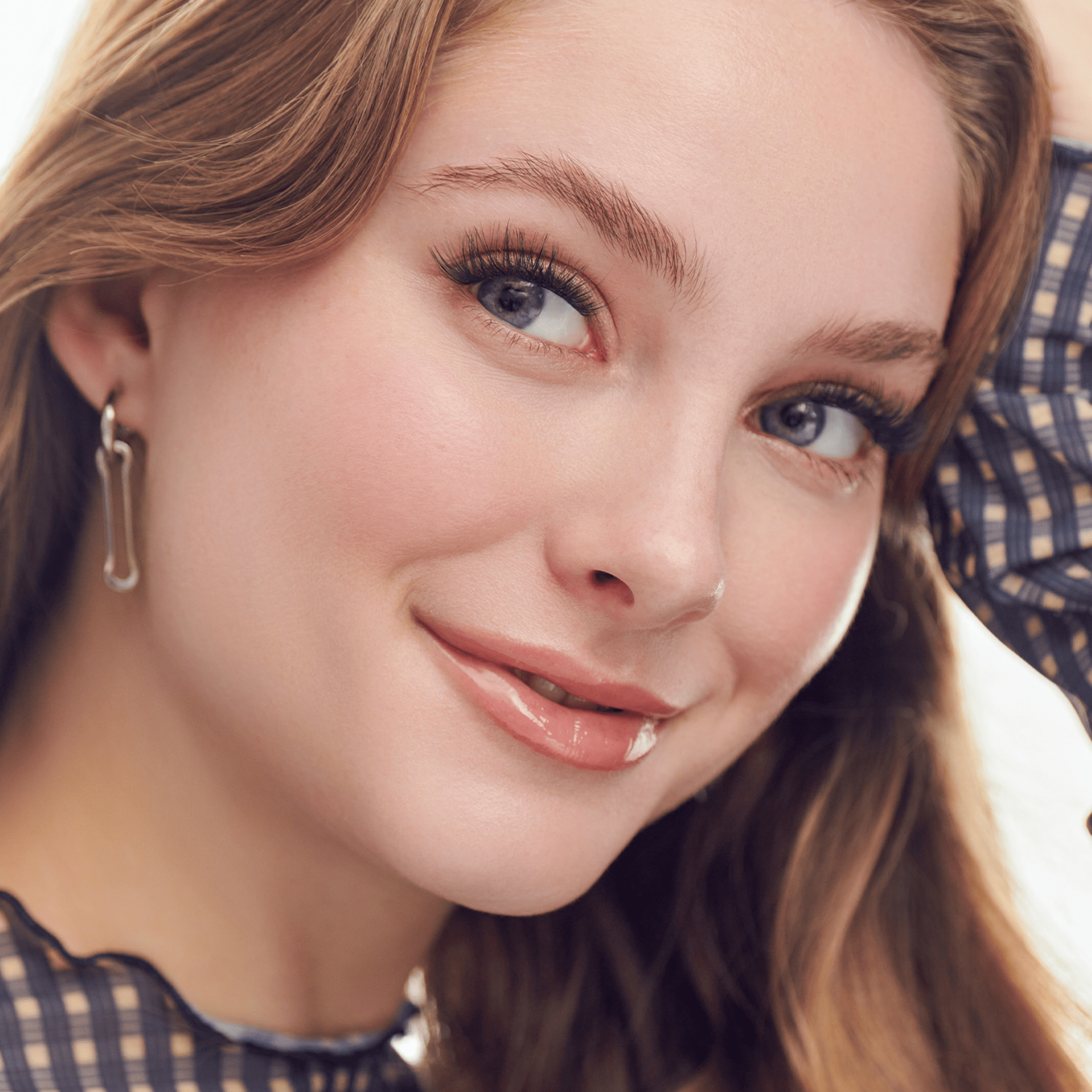 Close-up of a woman with styled hair and makeup, wearing earrings.