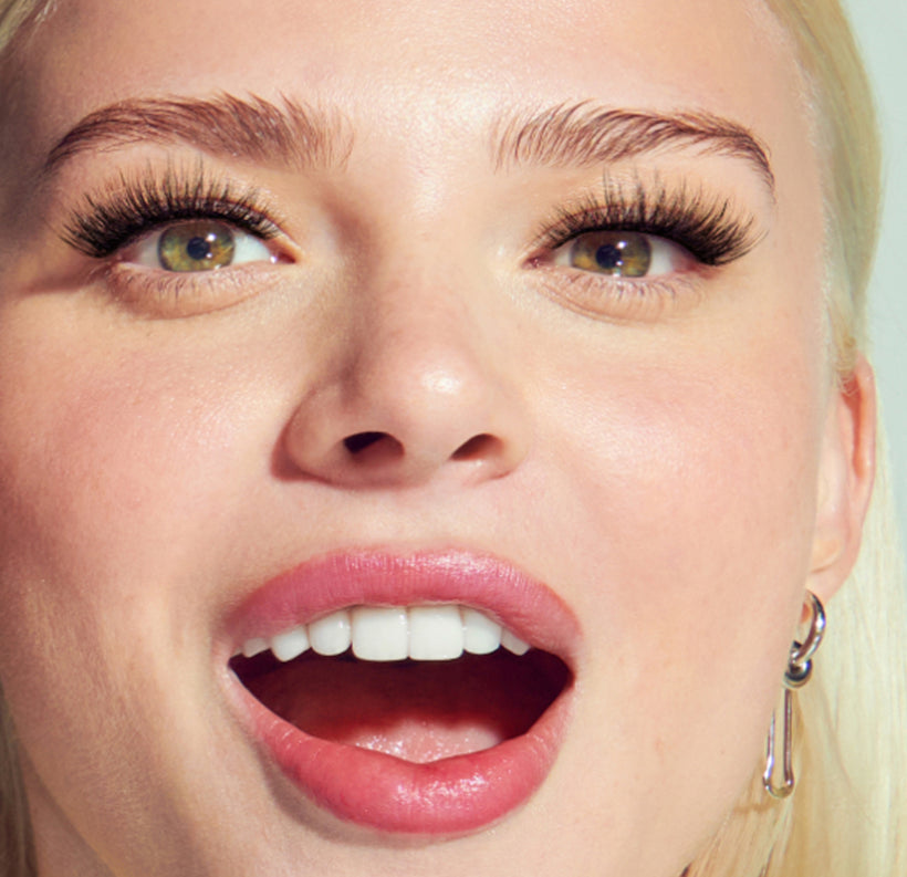 Close-up of woman's face with bold lashes and pink lipstick makeup look