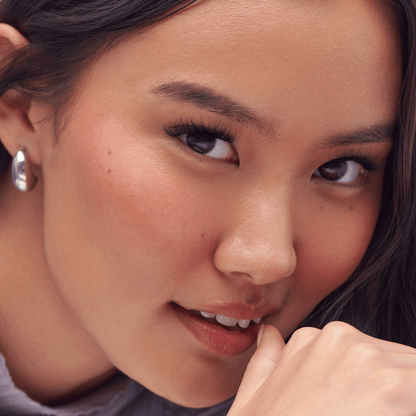 Close-up of a woman with a soft smile, wearing a silver earring.