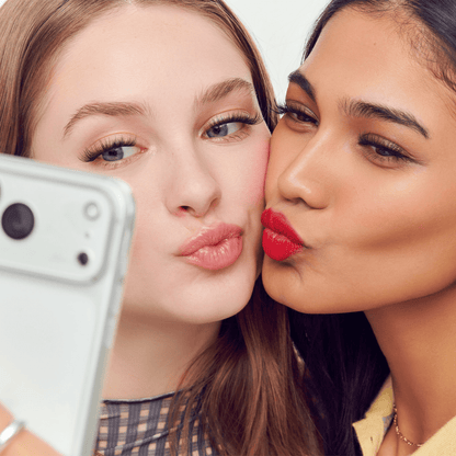 Two women taking a selfie with a smartphone, posing playfully.